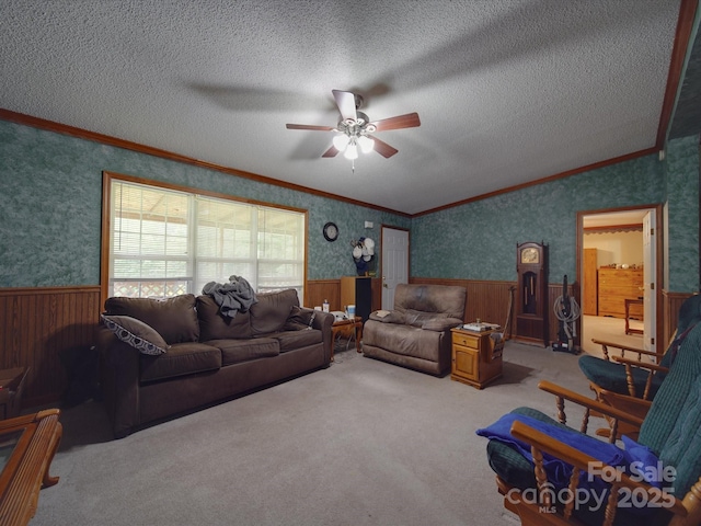 living area featuring wainscoting, ceiling fan, and crown molding
