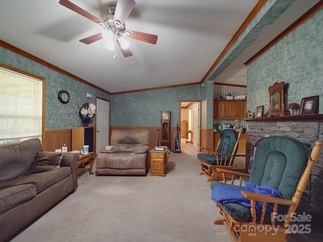 living area featuring carpet flooring, a wainscoted wall, a textured ceiling, ceiling fan, and ornamental molding