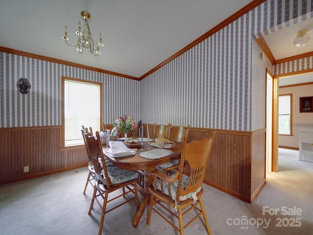 dining room featuring crown molding, wainscoting, and wallpapered walls