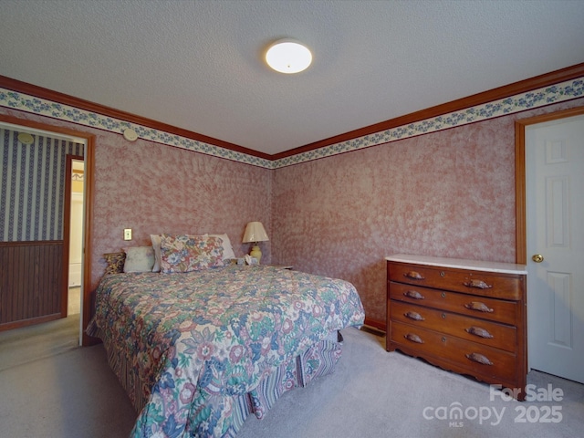 bedroom featuring light colored carpet, ornamental molding, a textured ceiling, and wallpapered walls
