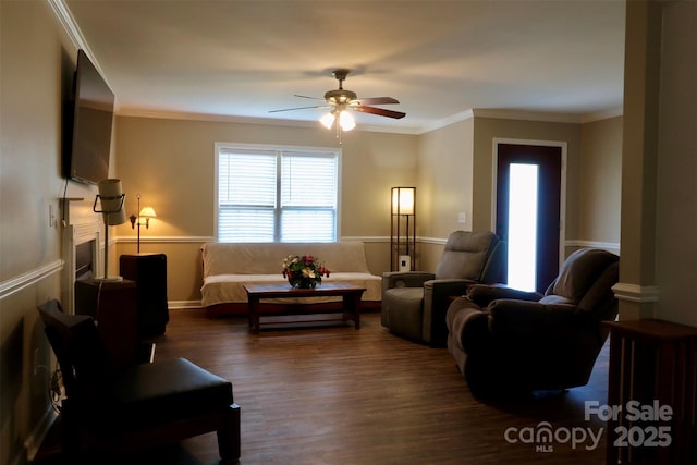 living room with a ceiling fan, baseboards, crown molding, and dark wood-style floors
