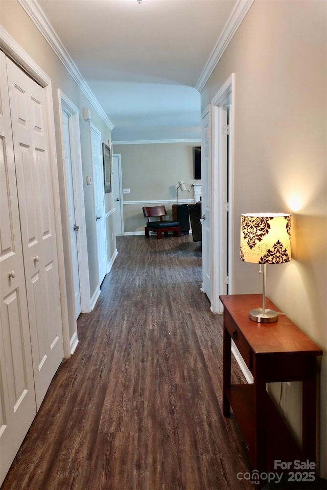 corridor with dark wood-style flooring, baseboards, and ornamental molding