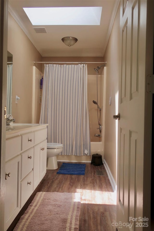 bathroom with crown molding, a skylight, toilet, and wood finished floors