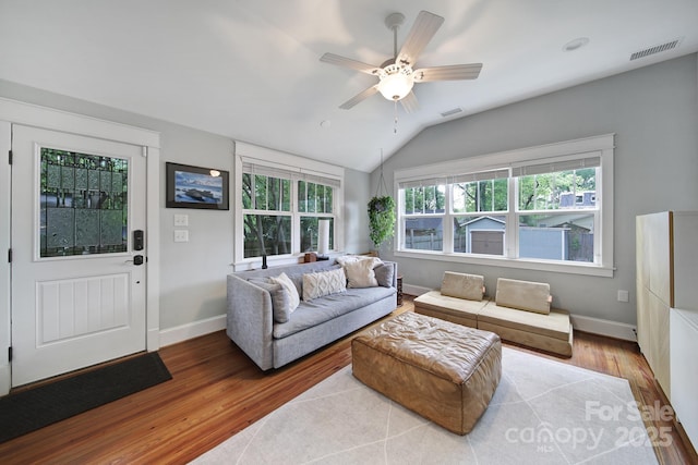 living area featuring wood finished floors, baseboards, ceiling fan, and vaulted ceiling