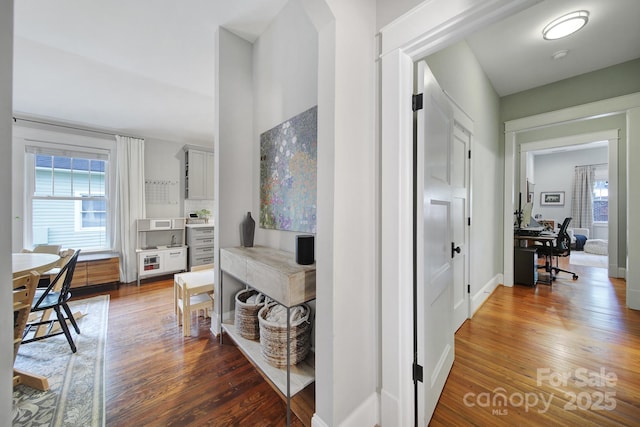 hall with a desk, wood finished floors, and baseboards