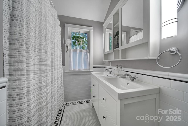 full bathroom with tile walls, a wainscoted wall, double vanity, and tile patterned floors