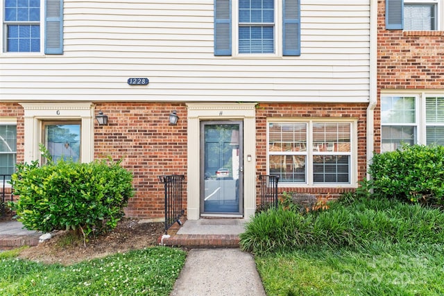 view of exterior entry featuring brick siding