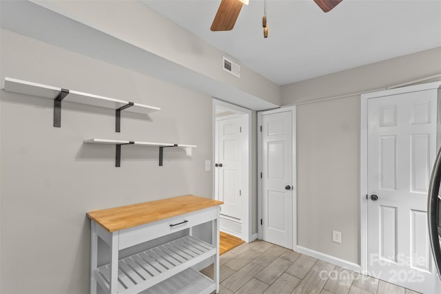 interior space featuring a ceiling fan, light wood-style floors, visible vents, and baseboards