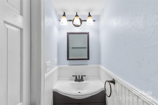 bathroom featuring a wainscoted wall, vanity, and a textured wall
