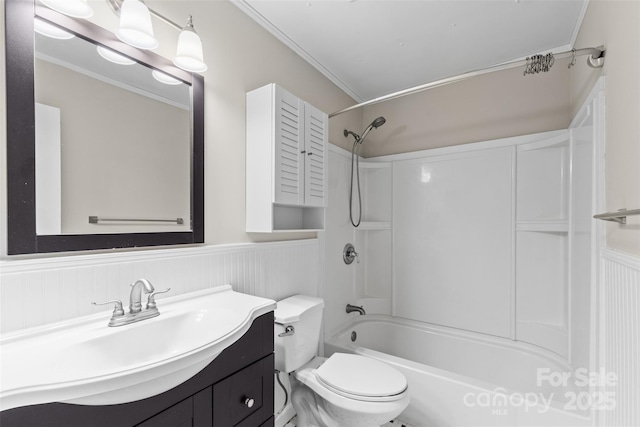 bathroom with toilet, ornamental molding, vanity, and a wainscoted wall
