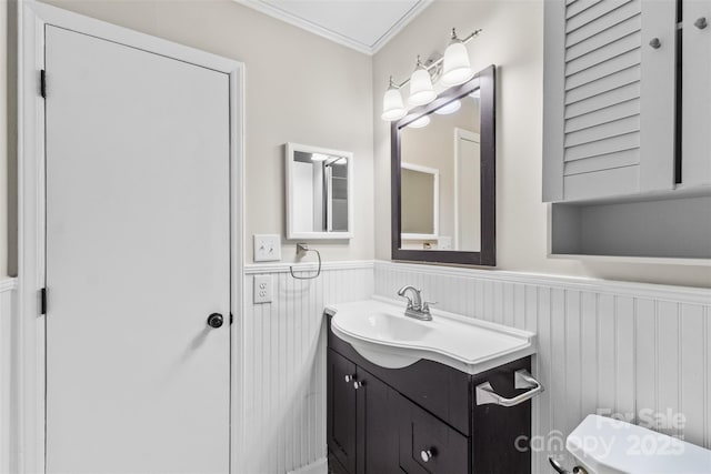 half bath featuring wainscoting, vanity, and crown molding