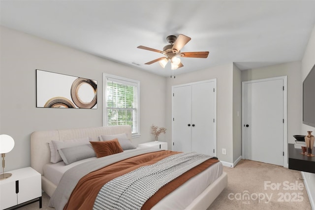 bedroom featuring a ceiling fan, a closet, baseboards, visible vents, and light carpet