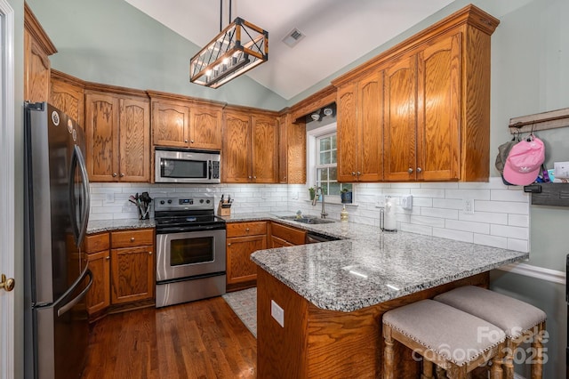 319 Beacon Hills Dr, Gastonia, NC 28056 - kitchen with stainless steel appliances, a sink, vaulted ceiling, a peninsula, and brown cabinetry