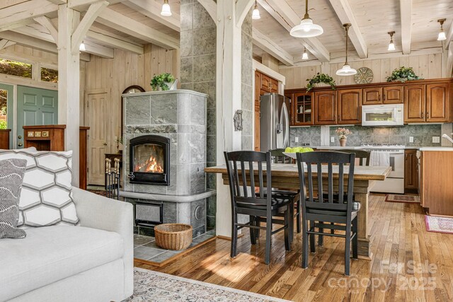 dining area with beamed ceiling, light wood-type flooring, wood ceiling, and a fireplace