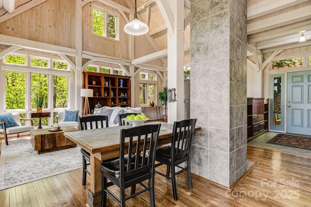 dining space with high vaulted ceiling, hardwood / wood-style floors, and beamed ceiling