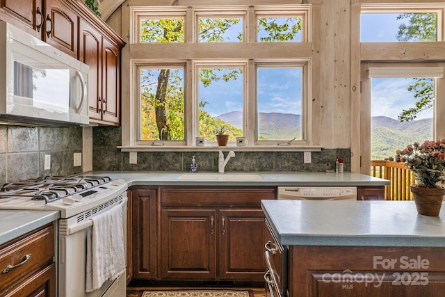 kitchen with white appliances, a sink, decorative backsplash, and a mountain view