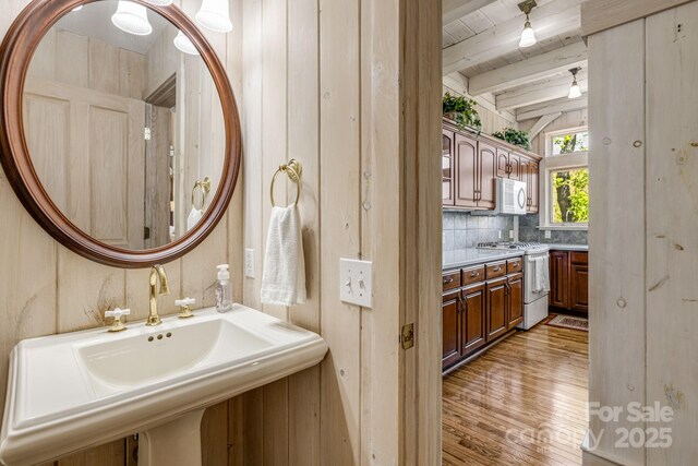 bathroom featuring a sink, wood finished floors, beamed ceiling, decorative backsplash, and wood ceiling