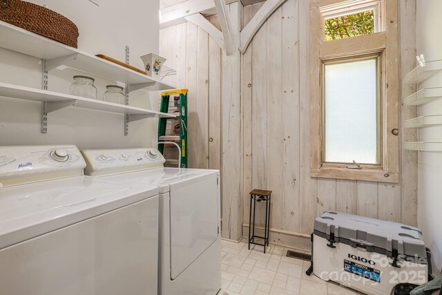 laundry room featuring wood walls and separate washer and dryer