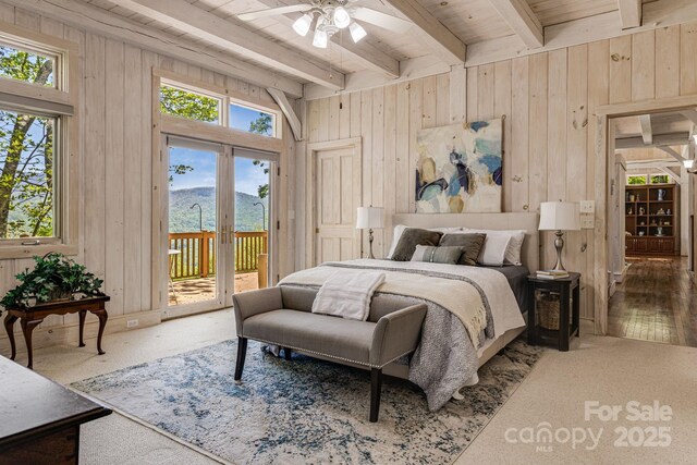 bedroom featuring access to exterior, multiple windows, beamed ceiling, wood walls, and wooden ceiling