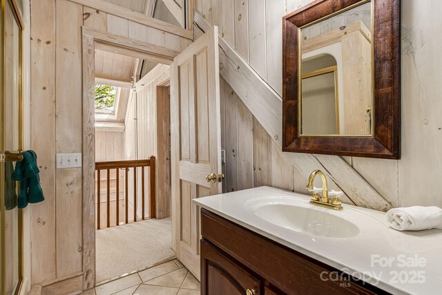 bathroom with wood walls, vanity, and tile patterned floors