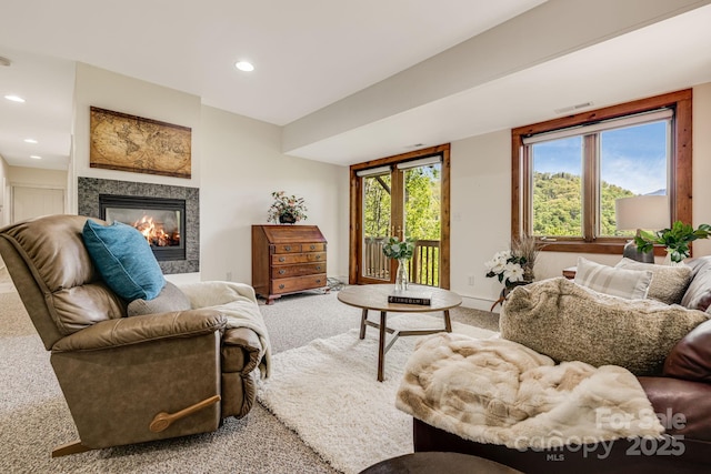living room featuring light carpet, a glass covered fireplace, recessed lighting, and baseboards