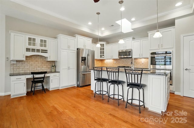 5028 Polo Gate Blvd, Charlotte, NC 28216 - kitchen featuring stainless steel appliances, a kitchen breakfast bar, a raised ceiling, light wood-style flooring, and white cabinetry