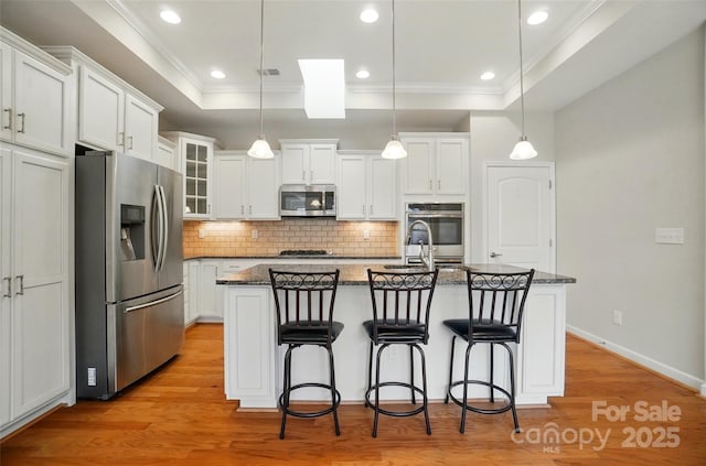 5028 Polo Gate Blvd, Charlotte, NC 28216 - kitchen with stainless steel appliances, a raised ceiling, tasteful backsplash, white cabinets, and a center island with sink