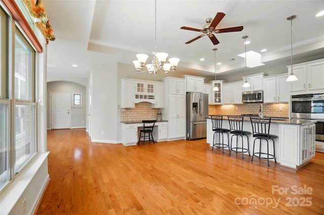 5028 Polo Gate Blvd, Charlotte, NC 28216 - kitchen featuring stainless steel appliances, a raised ceiling, arched walkways, a ceiling fan, and a kitchen bar