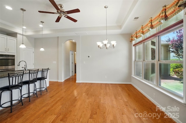 5028 Polo Gate Blvd, Charlotte, NC 28216 - dining space with arched walkways, a ceiling fan, a tray ceiling, light wood-style floors, and baseboards