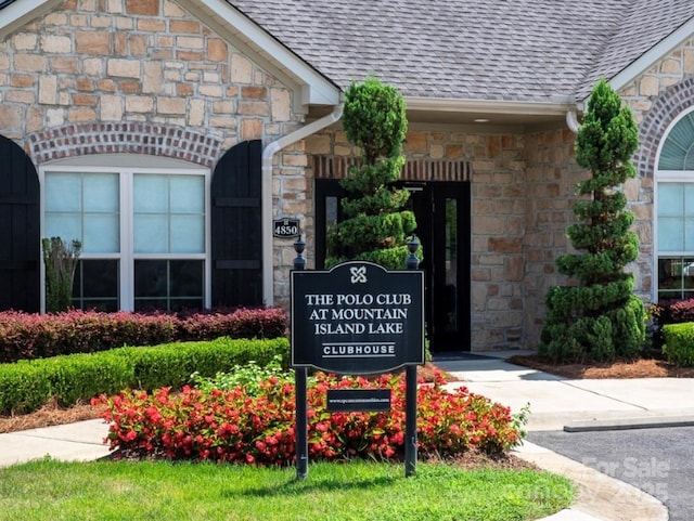5028 Polo Gate Blvd, Charlotte, NC 28216 - exterior view of stone siding, roof with shingles, a downspout, and gutters
