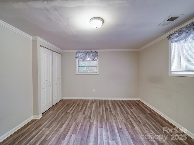 363 Sowers Rd, Linwood, NC 27299 - unfurnished bedroom featuring wood finished floors, multiple windows, baseboards, crown molding, and a closet