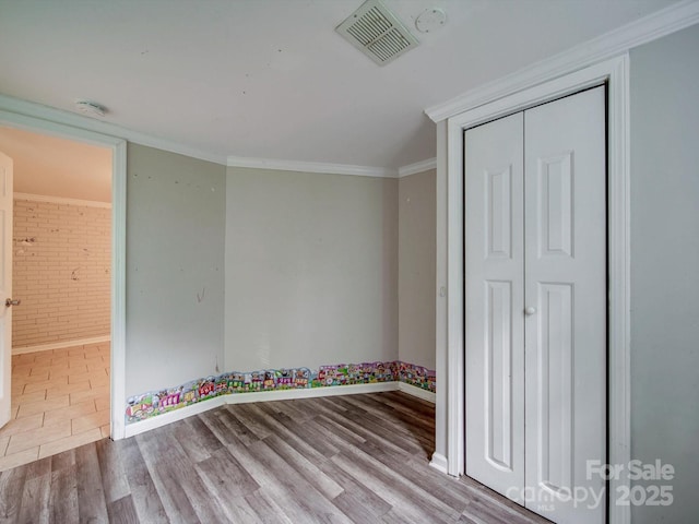 363 Sowers Rd, Linwood, NC 27299 - unfurnished bedroom with baseboards, wood finished floors, crown molding, a closet, and brick wall