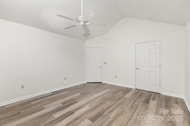 empty room featuring ceiling fan, baseboards, high vaulted ceiling, and wood finished floors