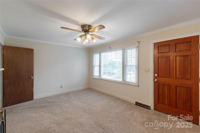 carpeted foyer entrance featuring crown molding, baseboards, and ceiling fan