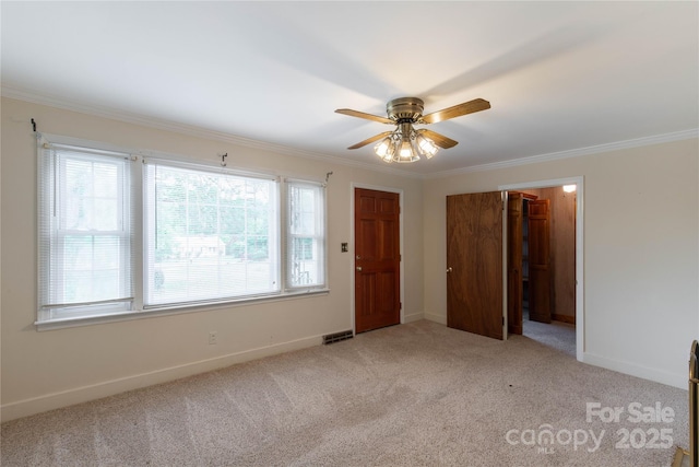 unfurnished bedroom with light carpet, ornamental molding, baseboards, and ceiling fan