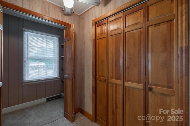 corridor with carpet, baseboards, and wood walls