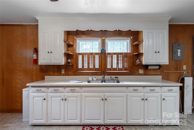 kitchen with a sink, open shelves, wood walls, light countertops, and crown molding