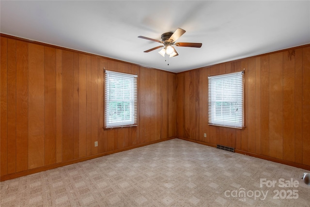 spare room with a ceiling fan and wooden walls