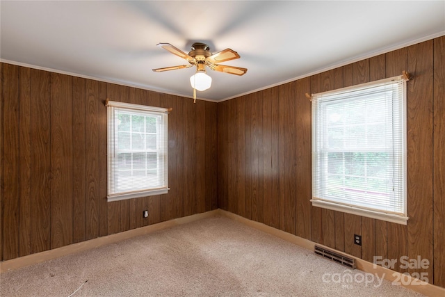 unfurnished room featuring a ceiling fan, carpet floors, wooden walls, and baseboards