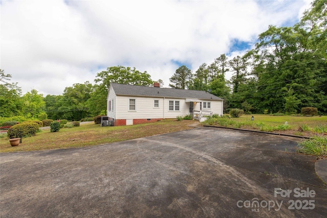 view of front of home featuring a front yard, crawl space, a chimney, and asphalt driveway