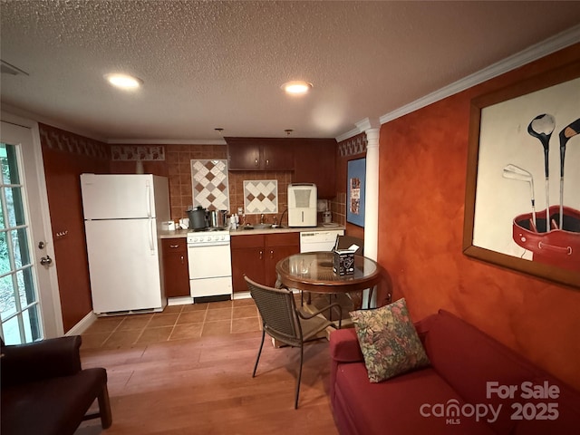 kitchen with a sink, white appliances, tasteful backsplash, a textured ceiling, and light countertops
