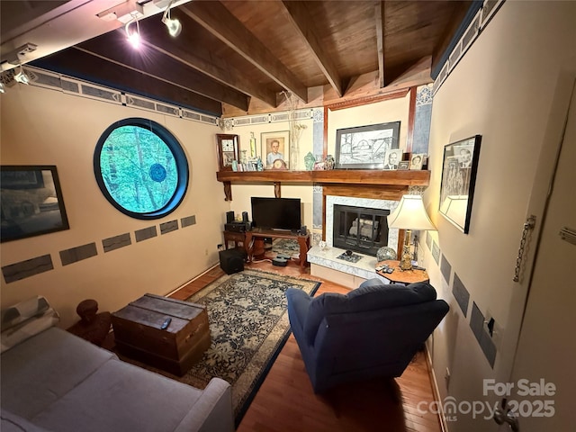 living room featuring a glass covered fireplace, wood ceiling, track lighting, wood finished floors, and beam ceiling