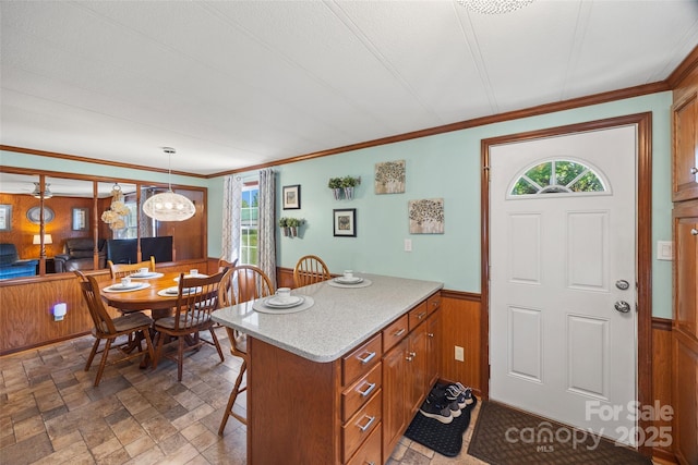 105 Carrie Ln Unit 3, Cherryville, NC 28021 - kitchen with stone finish floor, brown cabinetry, a kitchen bar, crown molding, and a wainscoted wall