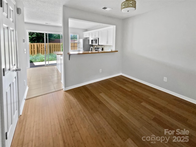 unfurnished dining area featuring visible vents, wood finished floors, and baseboards
