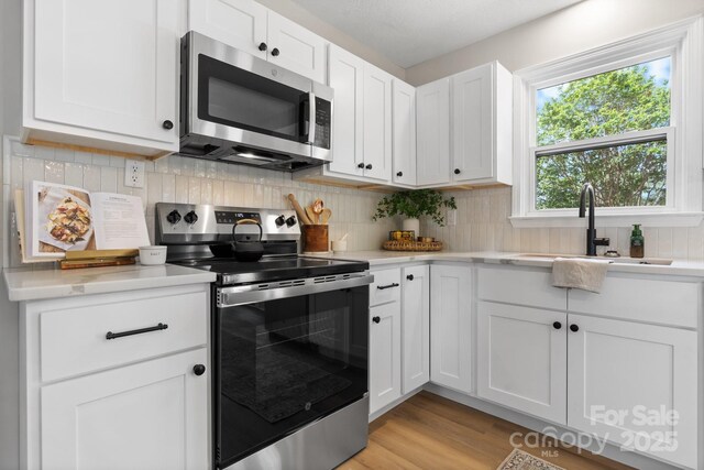 606 Hillcrest St, Hudson, NC 28638 - kitchen with light countertops, white cabinetry, stainless steel appliances, and light wood-style floors