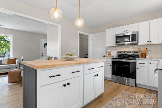 606 Hillcrest St, Hudson, NC 28638 - kitchen featuring wooden counters, light wood-style flooring, backsplash, decorative light fixtures, and appliances with stainless steel finishes