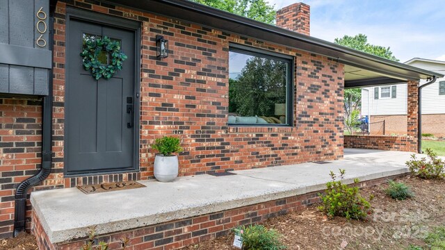 606 Hillcrest St, Hudson, NC 28638 - view of exterior entry with a chimney, brick siding, and covered porch