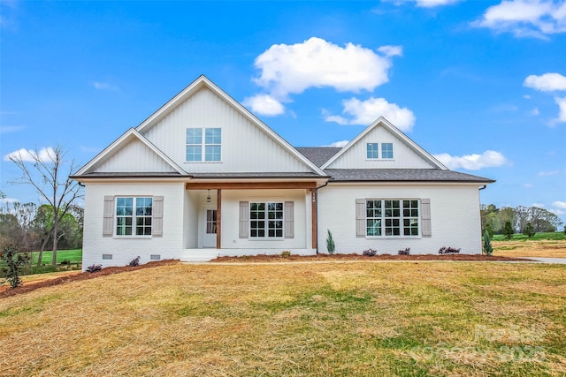 modern farmhouse with a porch, a front lawn, brick siding, and board and batten siding
