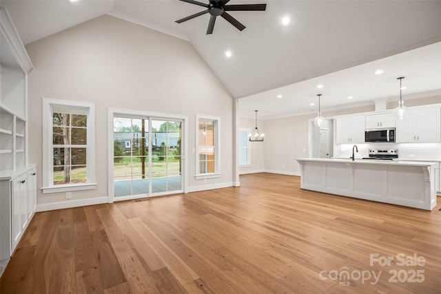unfurnished living room with recessed lighting, a sink, ceiling fan with notable chandelier, high vaulted ceiling, and light wood-style floors