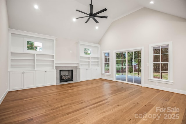 unfurnished living room with ceiling fan, a tile fireplace, light wood finished floors, and high vaulted ceiling